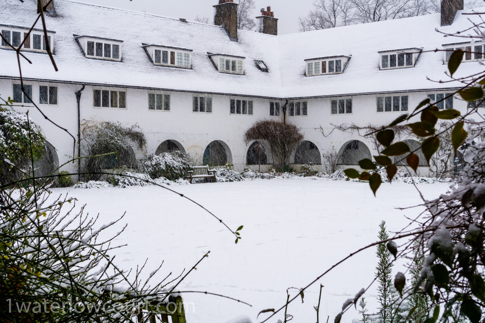 The central communal garden at Waterlow Court, covered in snow. Waterlow Court is an Arts & Crafts Grade II* listed building, designed by M. H. Baillie Scott, 1909, located in Hampstead Garden Suburb, London NW11 7DT. Flat 1, a one-bedroom, ground-floor flat, is for sale. Listed on Rightmove and Zoopla.